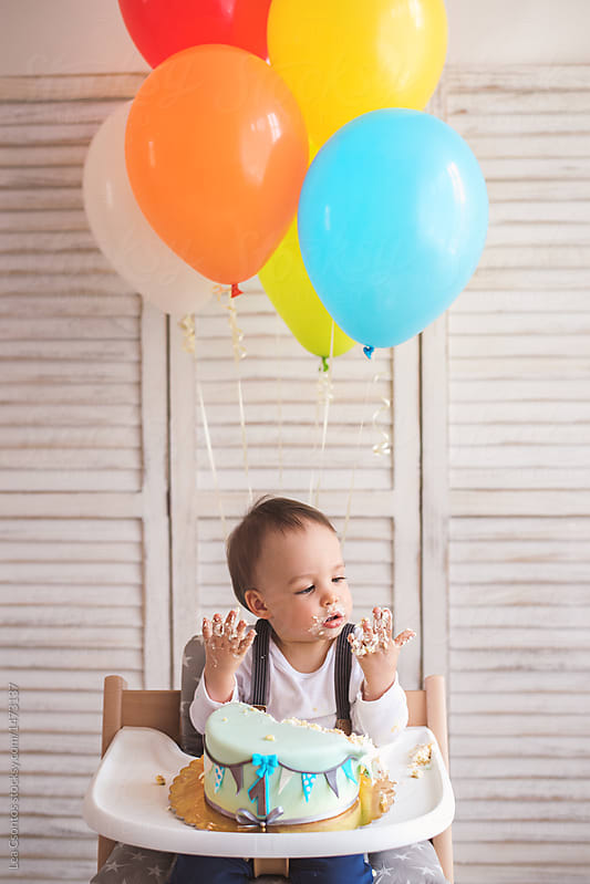 Cute little boy with colorful balloons eating his birthday cake