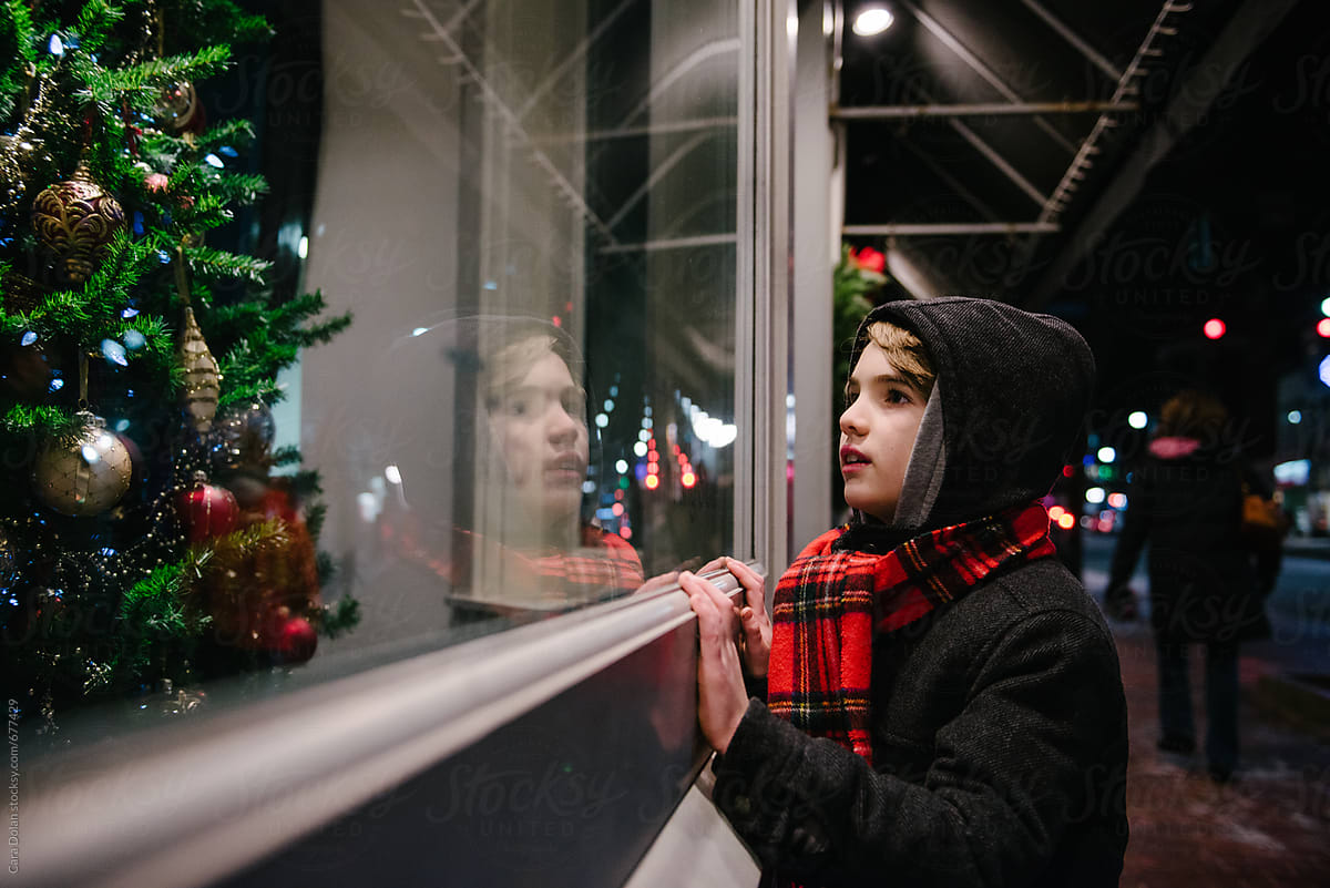 Young boy looks through at shop window at Christmas