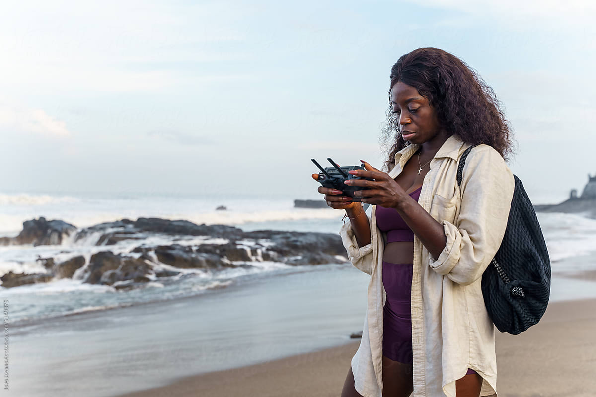 Woman with a modern drone controller at the beach
