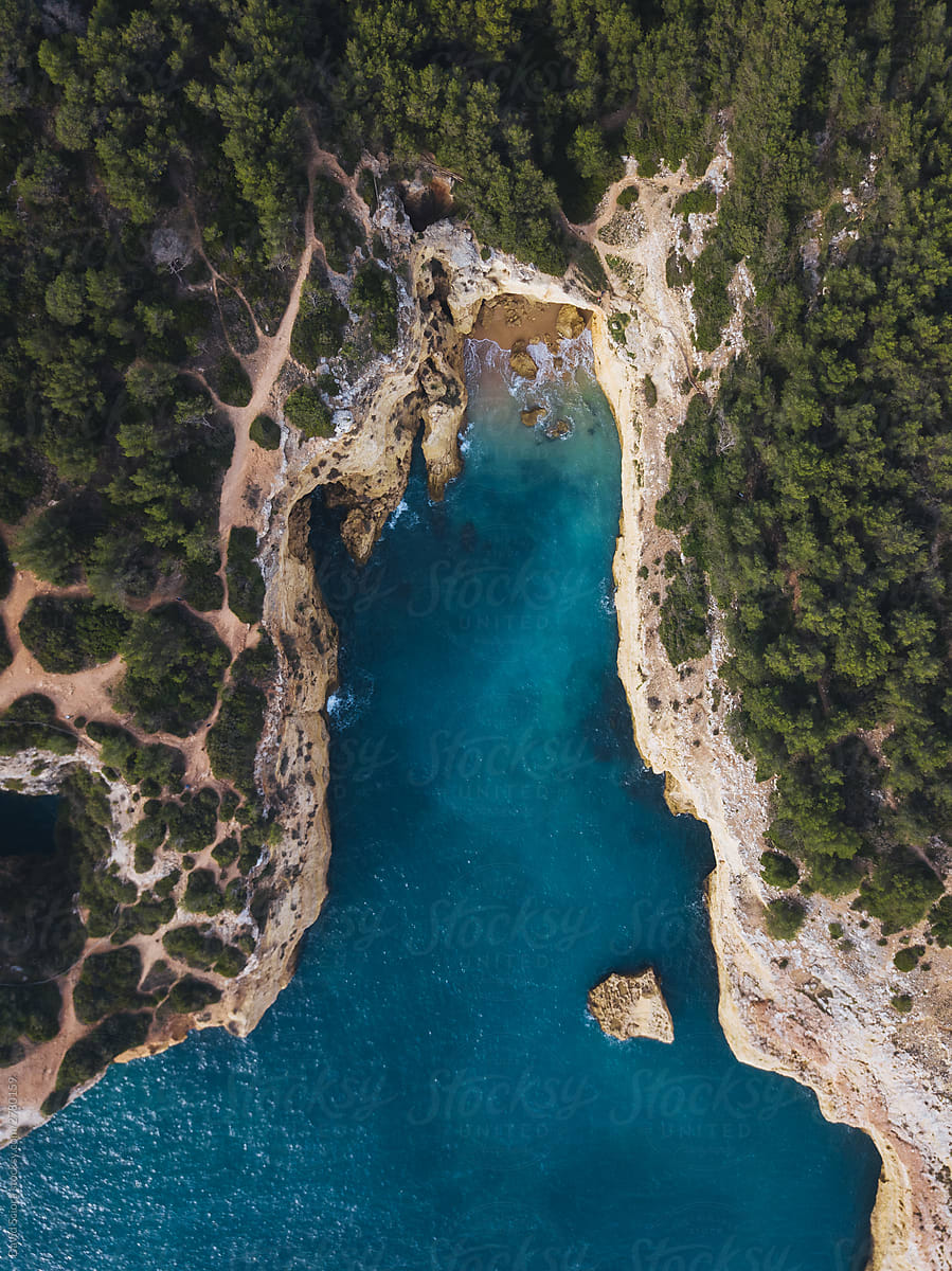 Aerial view of a small beach hidden between cliffs and forest