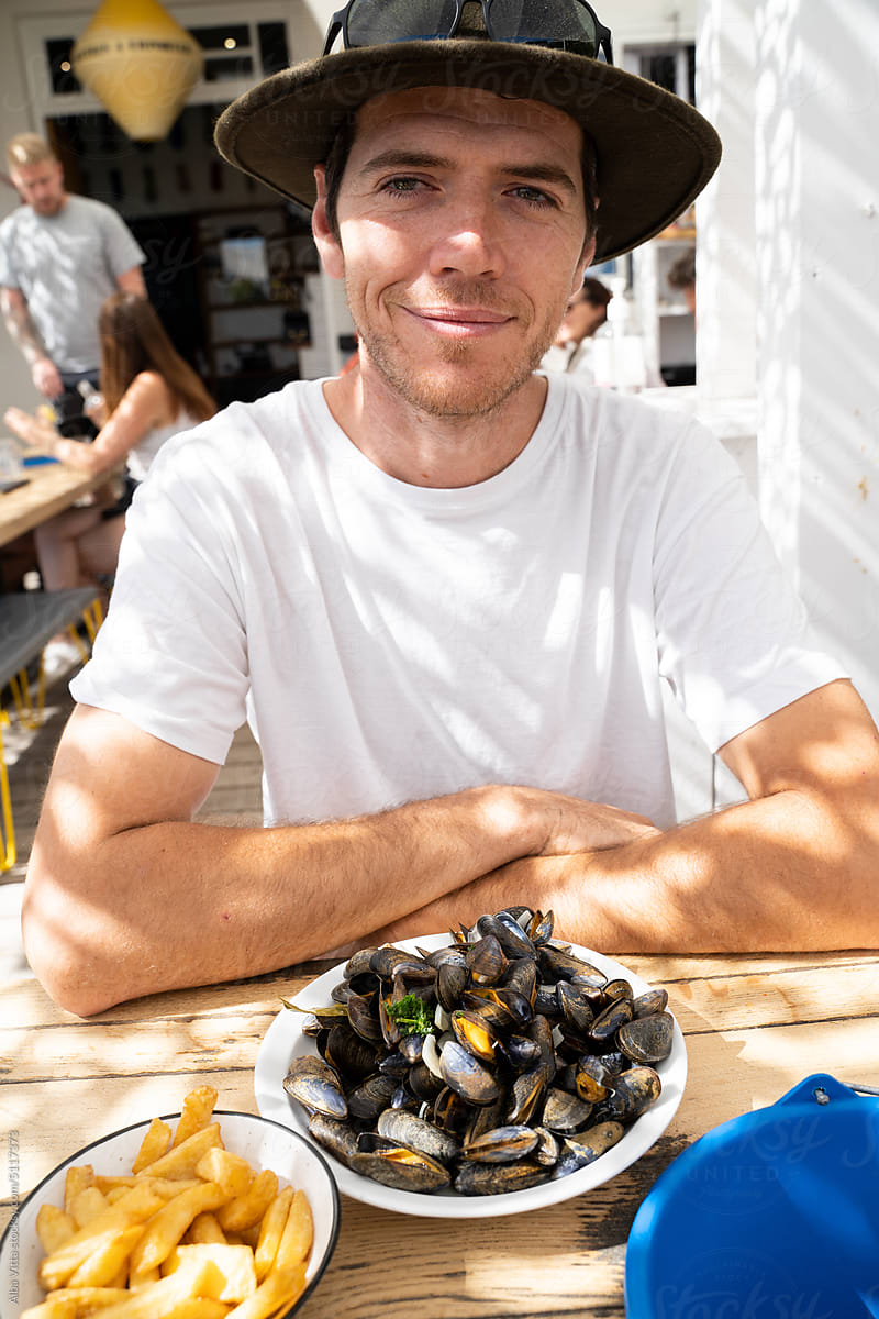 Man eating mussels and fries in restaurant