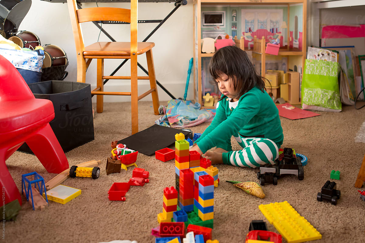 Girl in Christmas pajamas surrounded by playroom toys