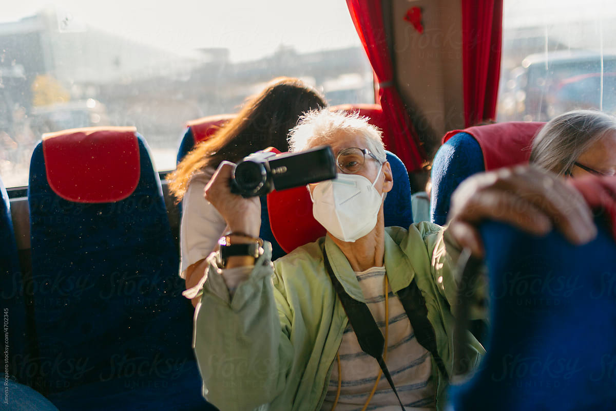 Tourist Senior man filming with video-camera inside inter-city bus