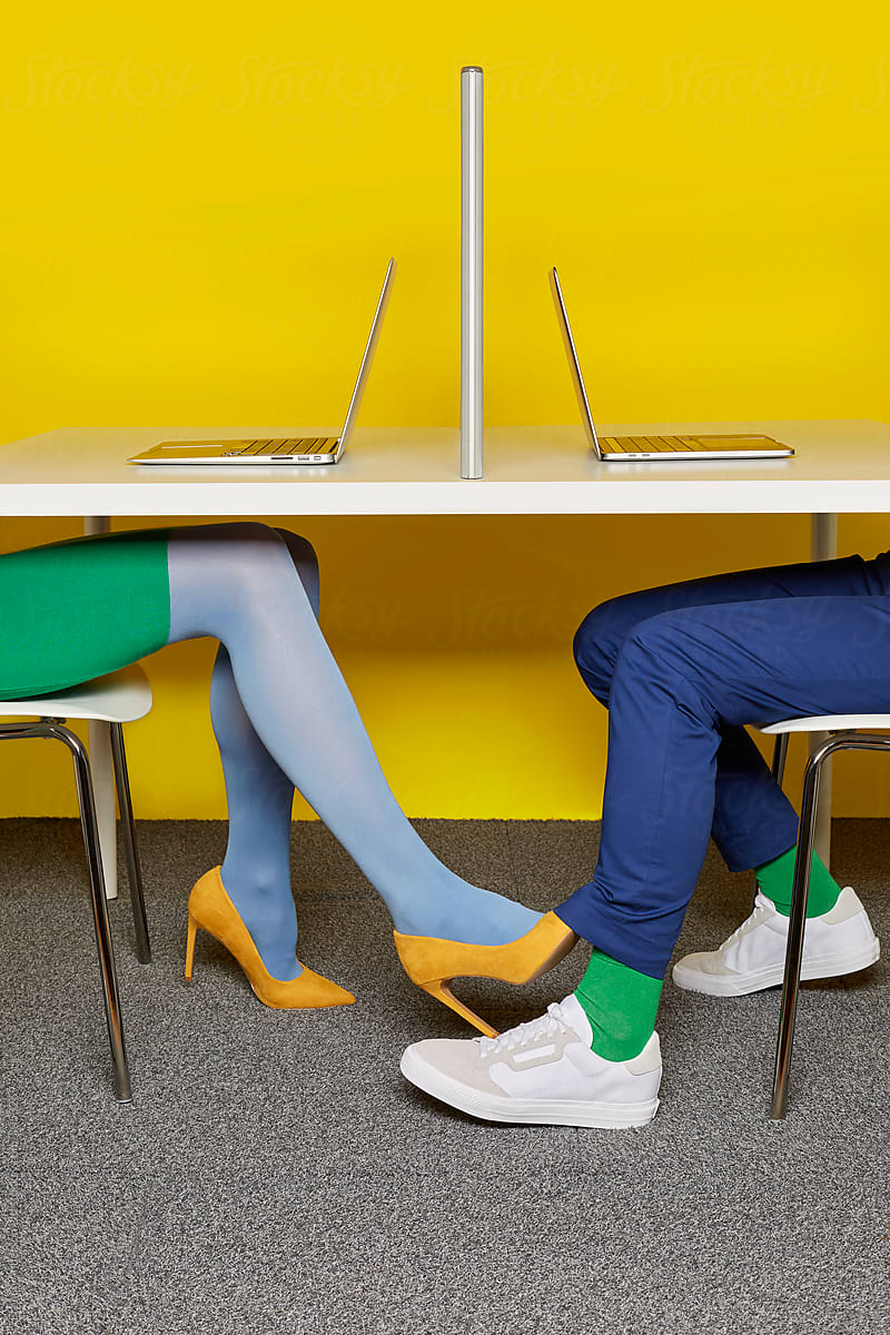 Two People Having An Office Romance Under A Desk By Stocksy