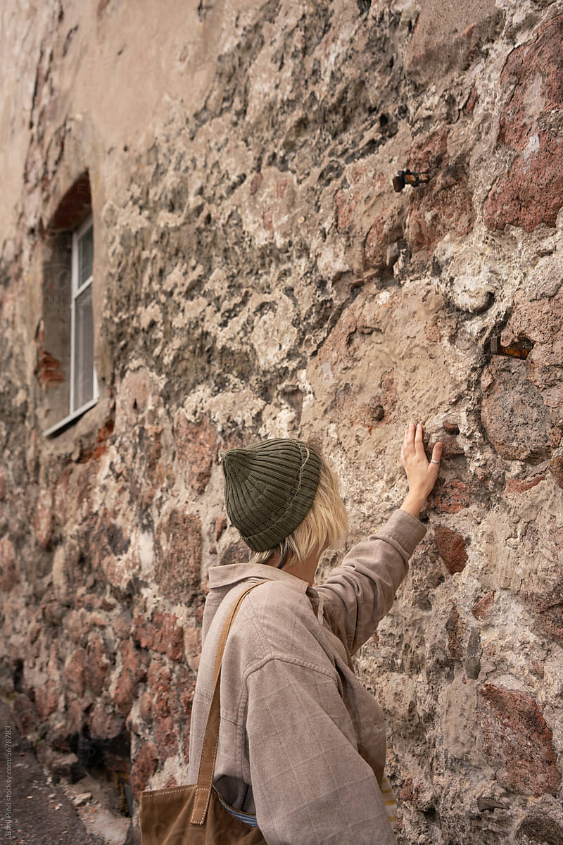 female tourist touching old building wall