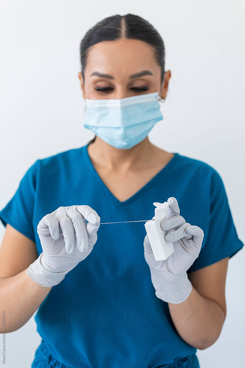 A dentist holding dental floss in front of a white wall