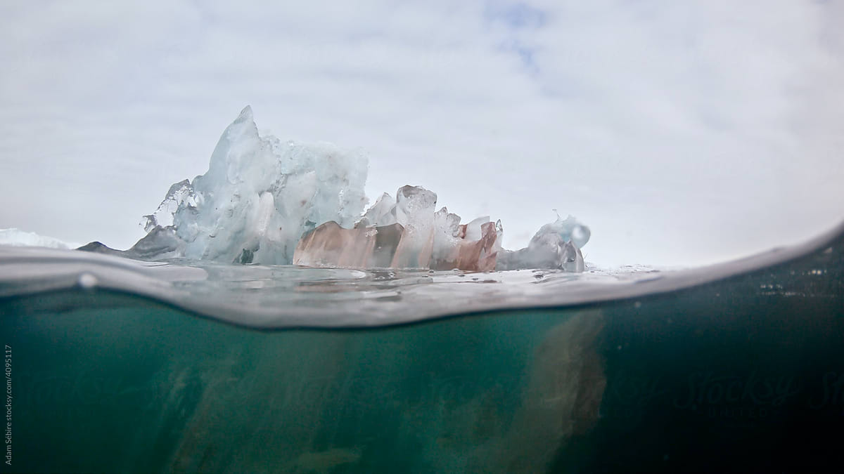 Melting translucent bergy bit of ice on water-line, Arctic Greenland