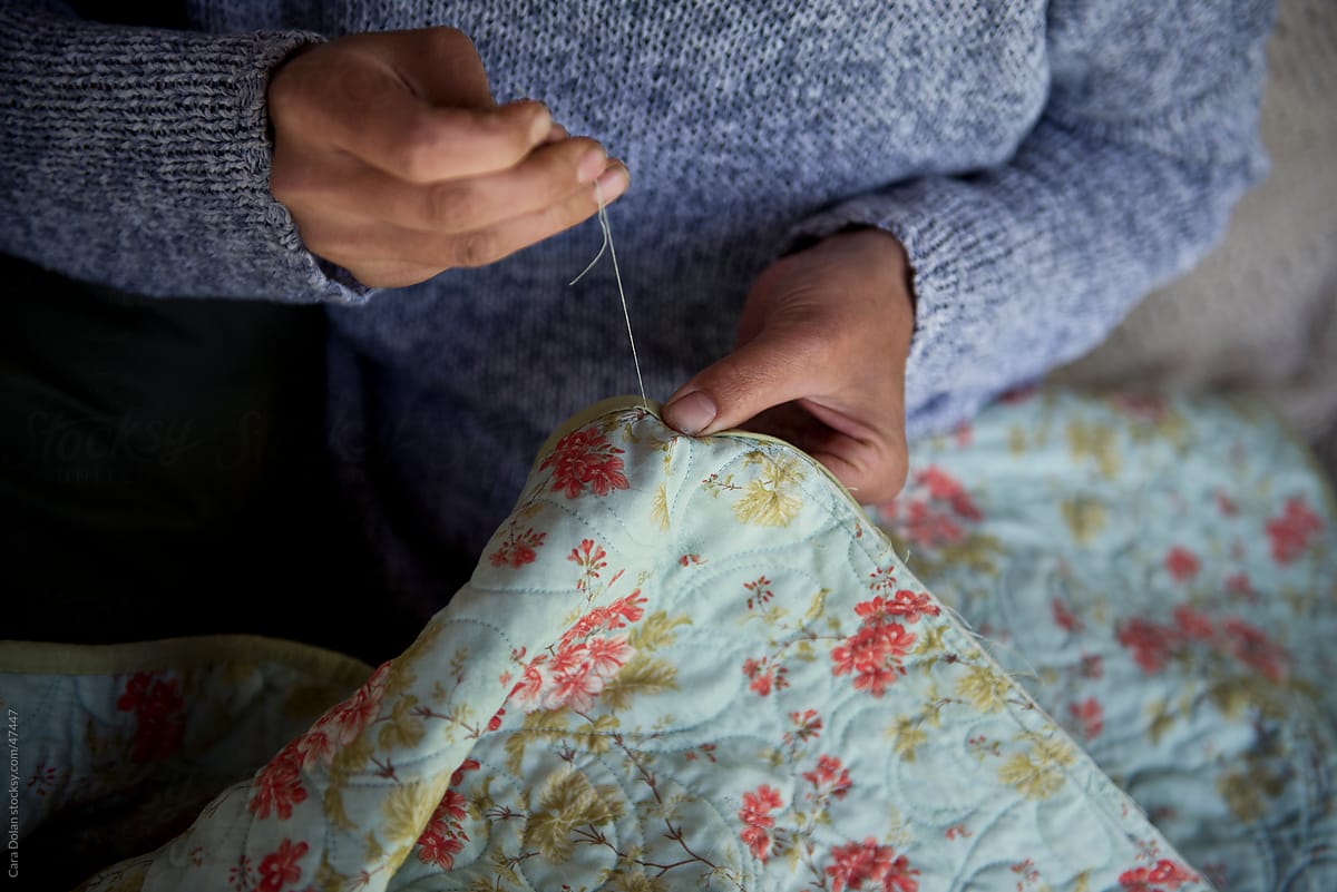 Woman hand sews a quilt