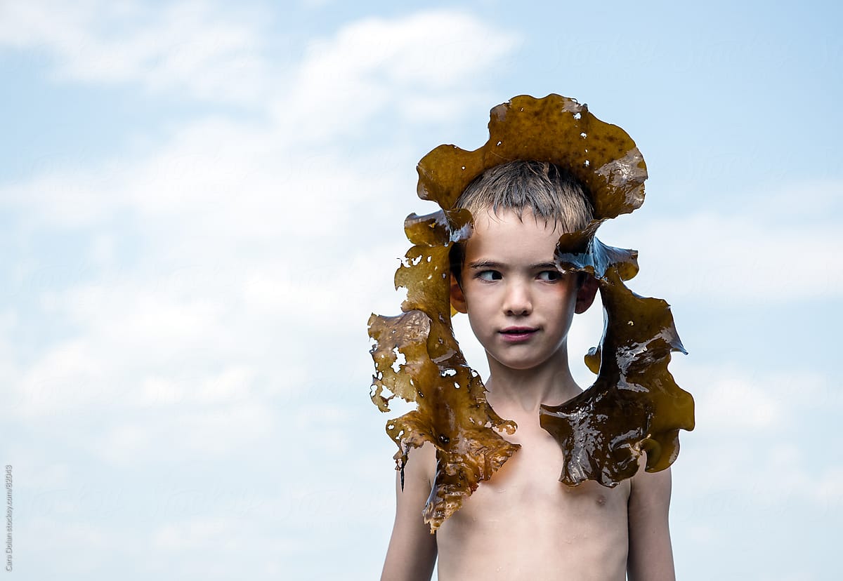 Silly Boy Playing Outside With Piece Of Kelp Seaweed by Stocksy