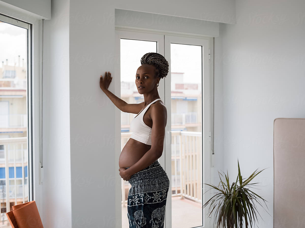 Black woman awaiting baby leaning on wall