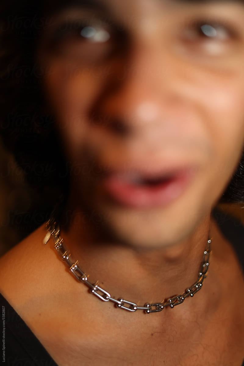 Blurred close-up portrait of man talking and wearing a silver chain