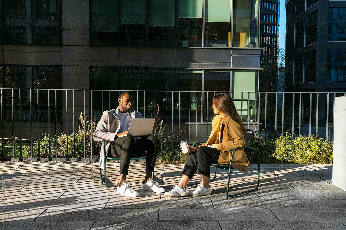 Two colleagues talking on the terrace of a modern corporate building