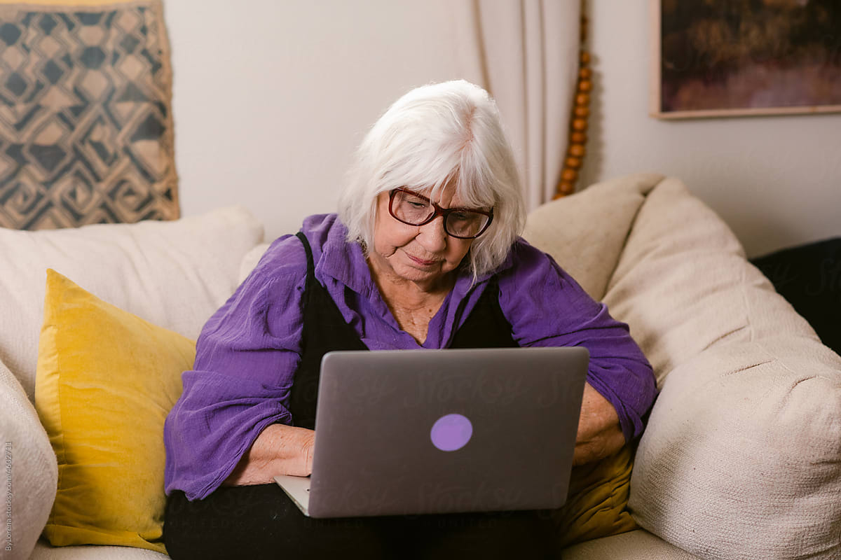 White-haired senior woman using laptop at home