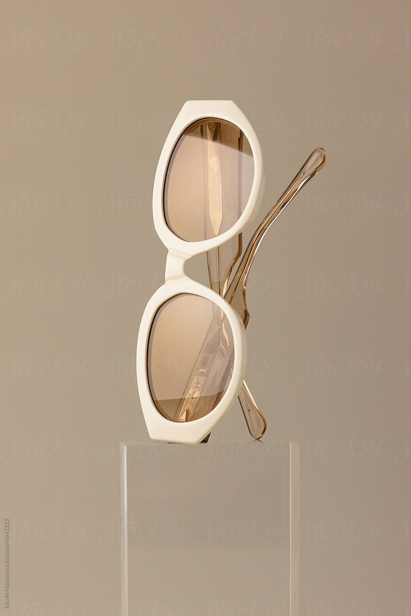 pair of sunglasses with golden lenses sitting on clear acrylic block