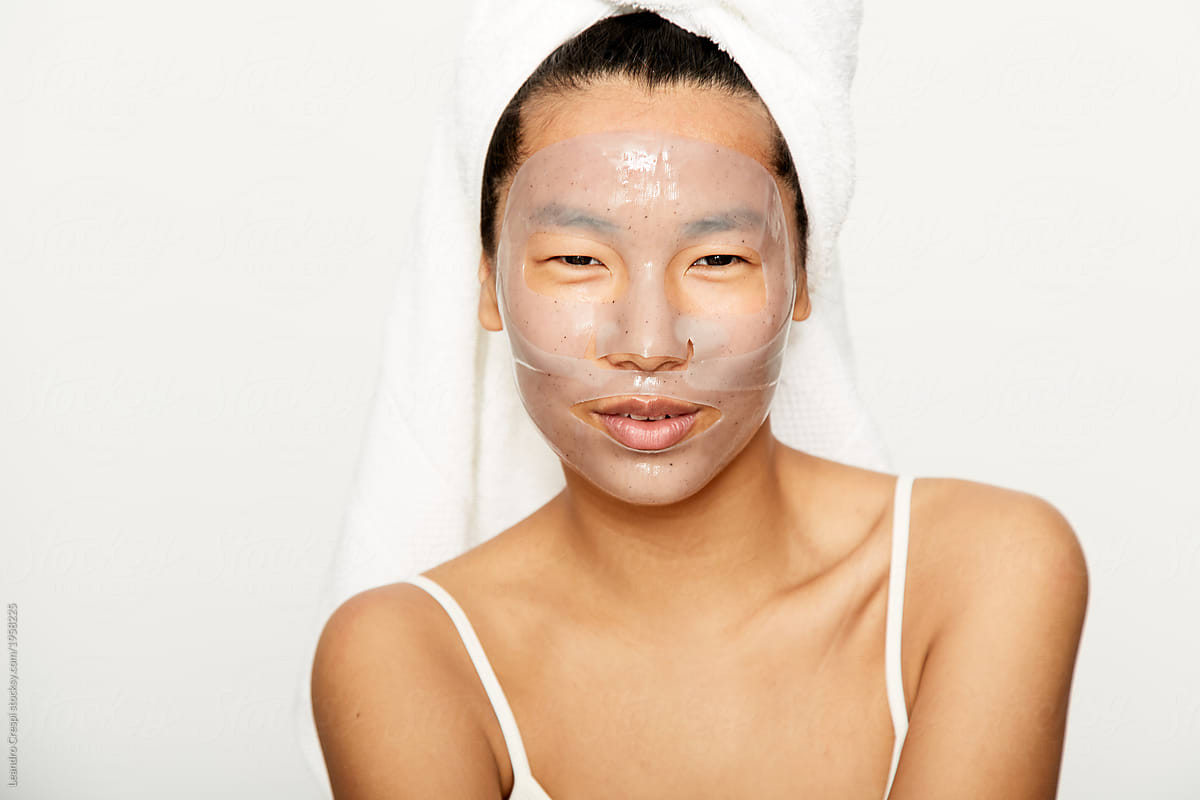 Young asian woman smiling with facial gel mask on during skincare treatment