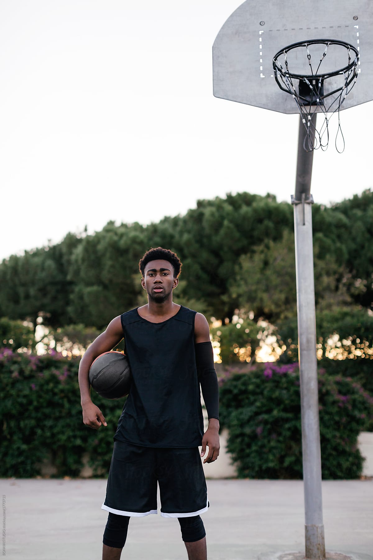 Portrait of a black man playing basketball on outdoor court.