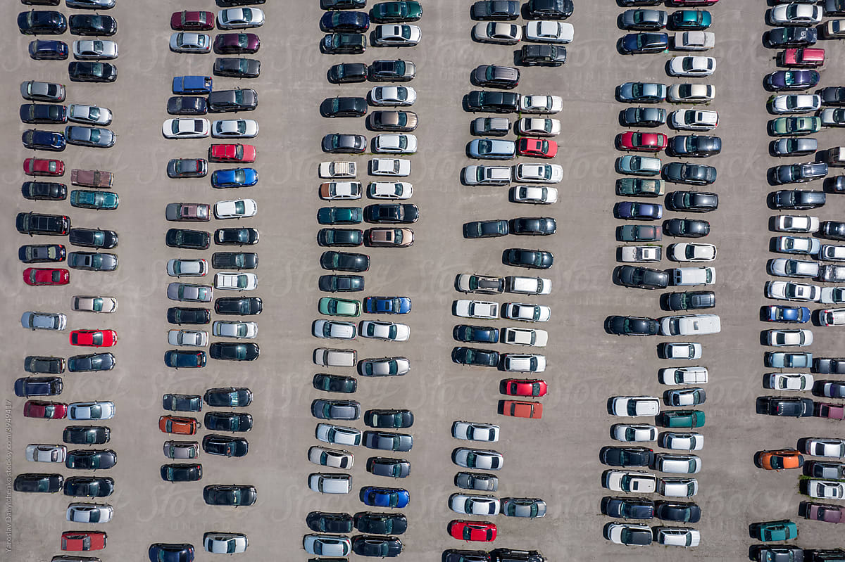 Bird's-eye view of numerous autos standing in rows on parking lot