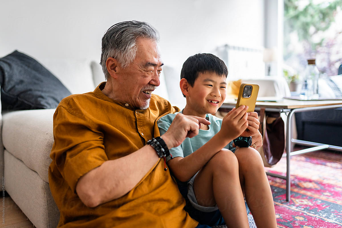 Chinese grandfather and grandson enjoy phone game.