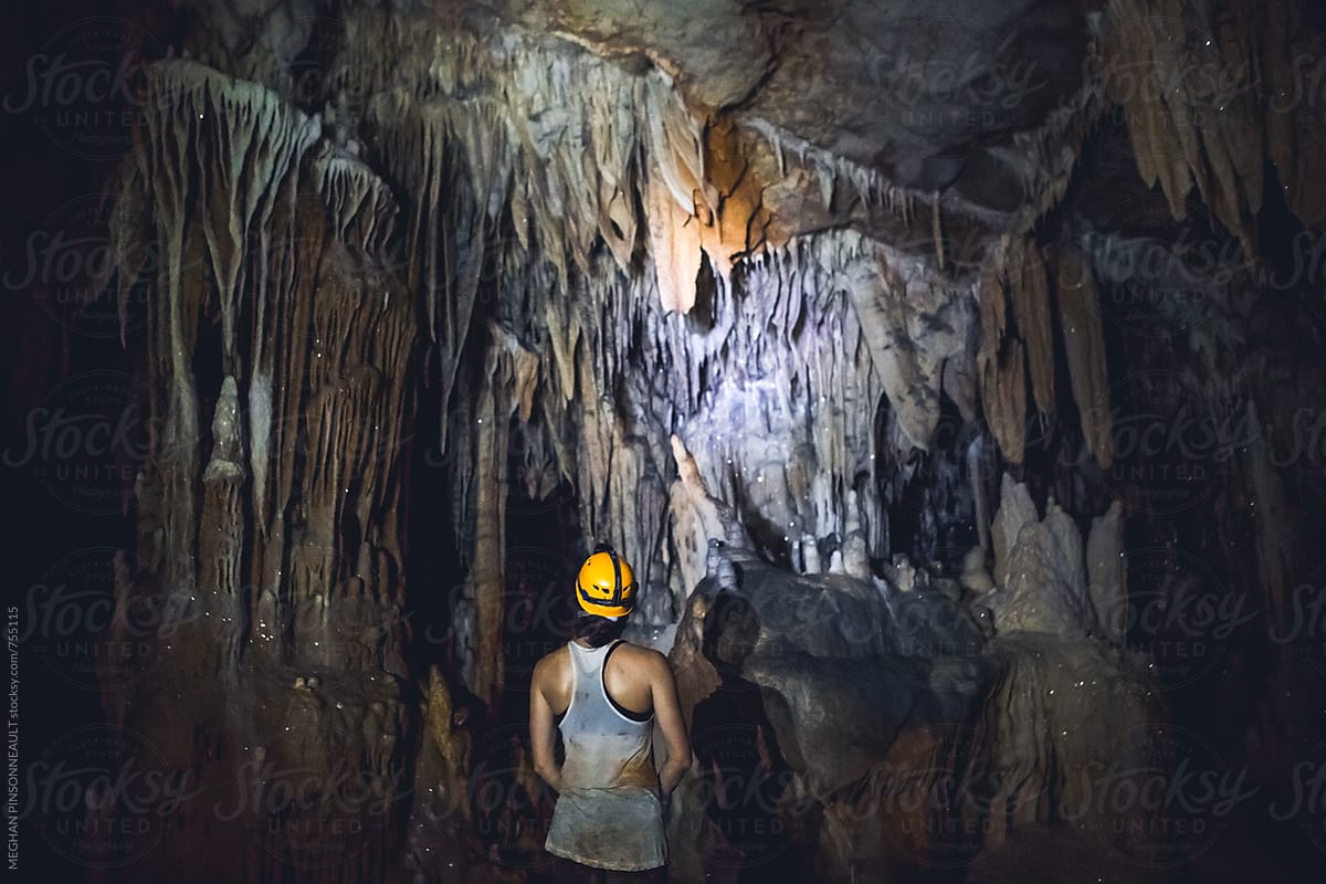 Woman Surrounded by Beautiful Stalactites in Cave