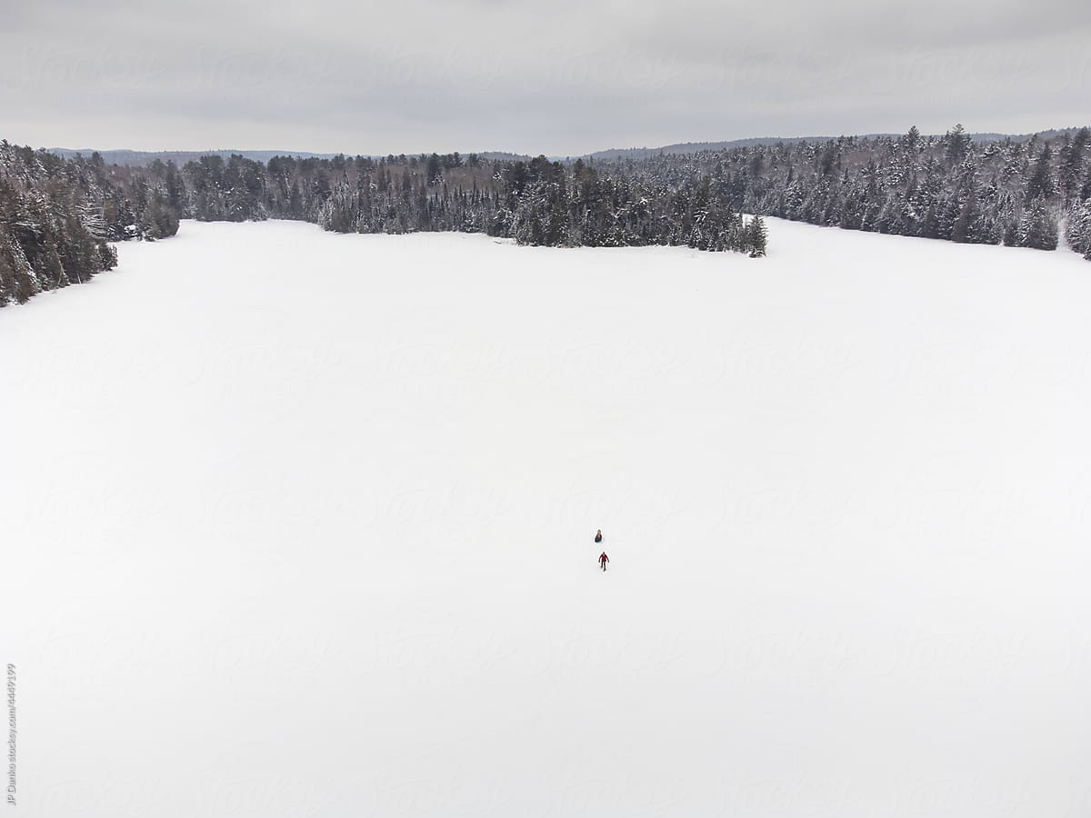 Snowshoeing Alone with Winter Camping Sled on Frozen Lake