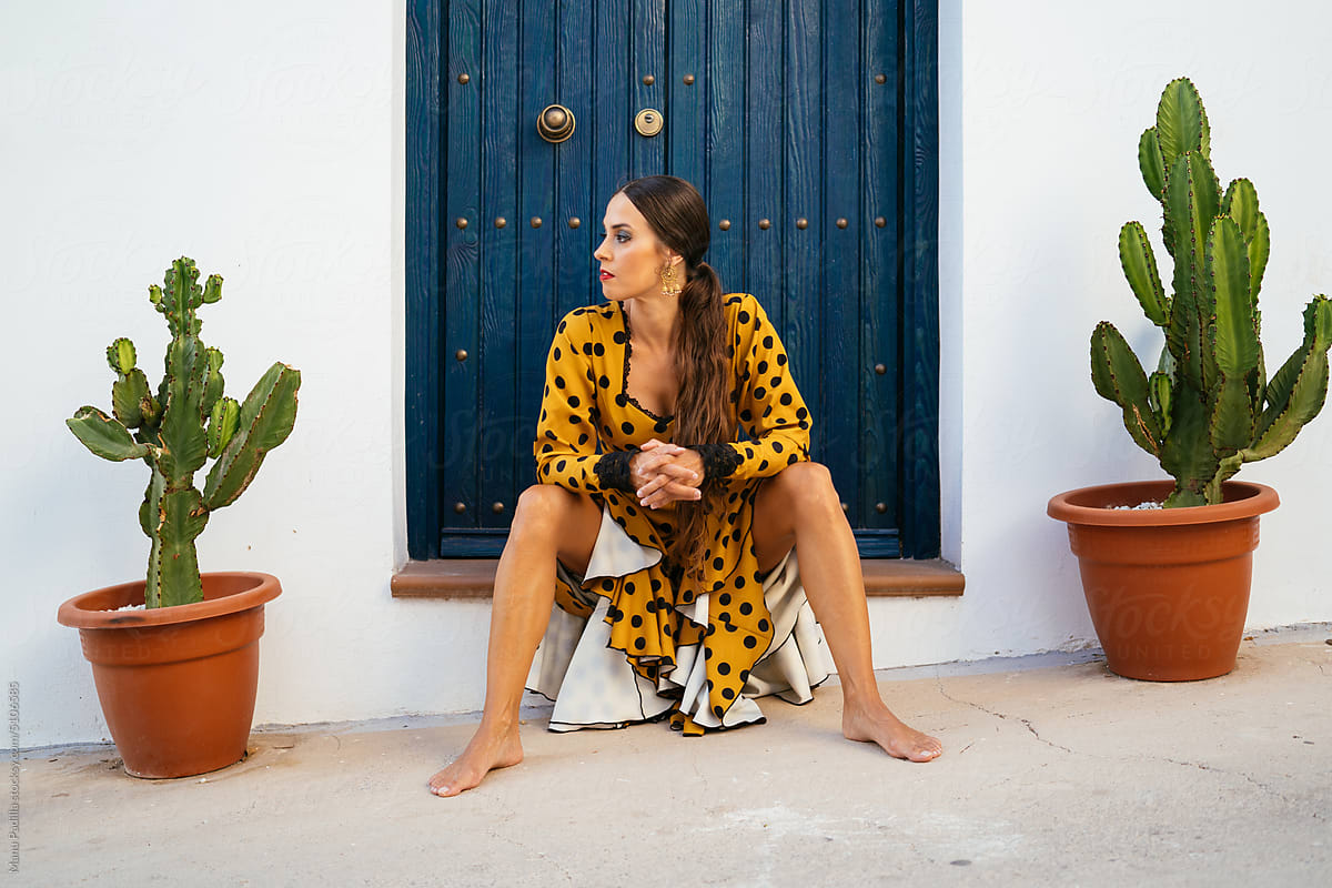 Female flamenco dancer resting at doorstep of house