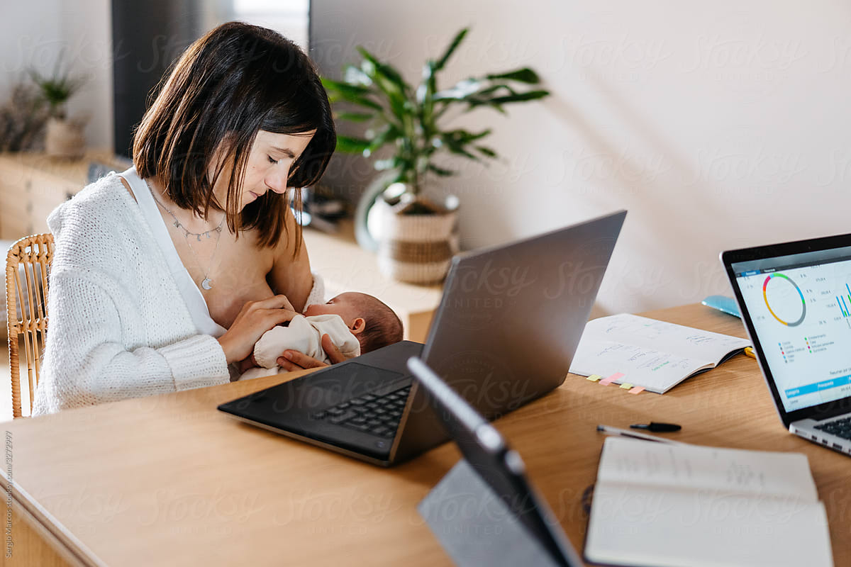 freelancer mom breastfeeding baby and working on laptop