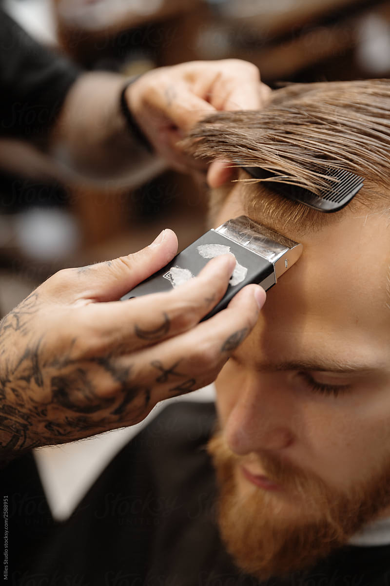Professional barber doing haircut to bearded man