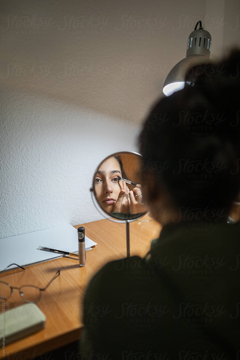 teenage girl doing makeup in her bedroom