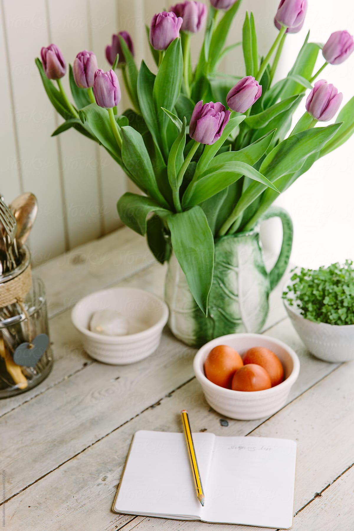 Kitchen counter, with black shopping list, spring flowers and kitchen essentials.