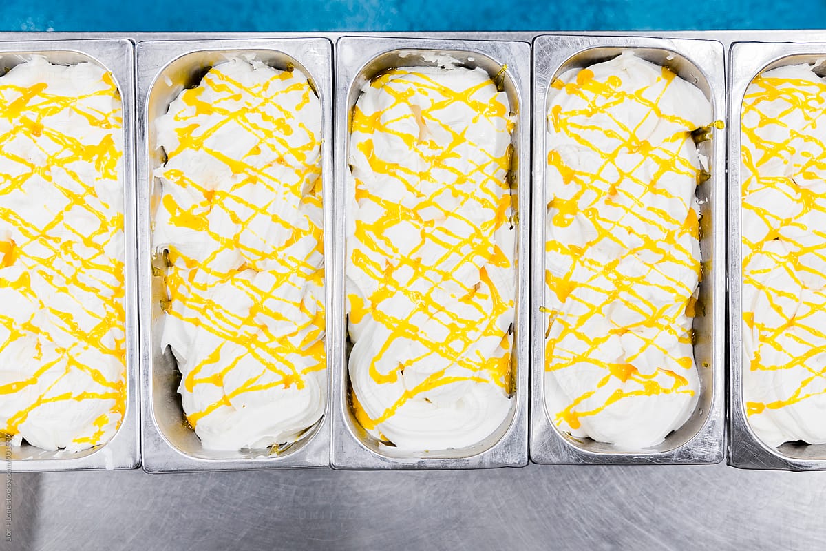 Industrial containers with vanilla ice cream and yellow sauce