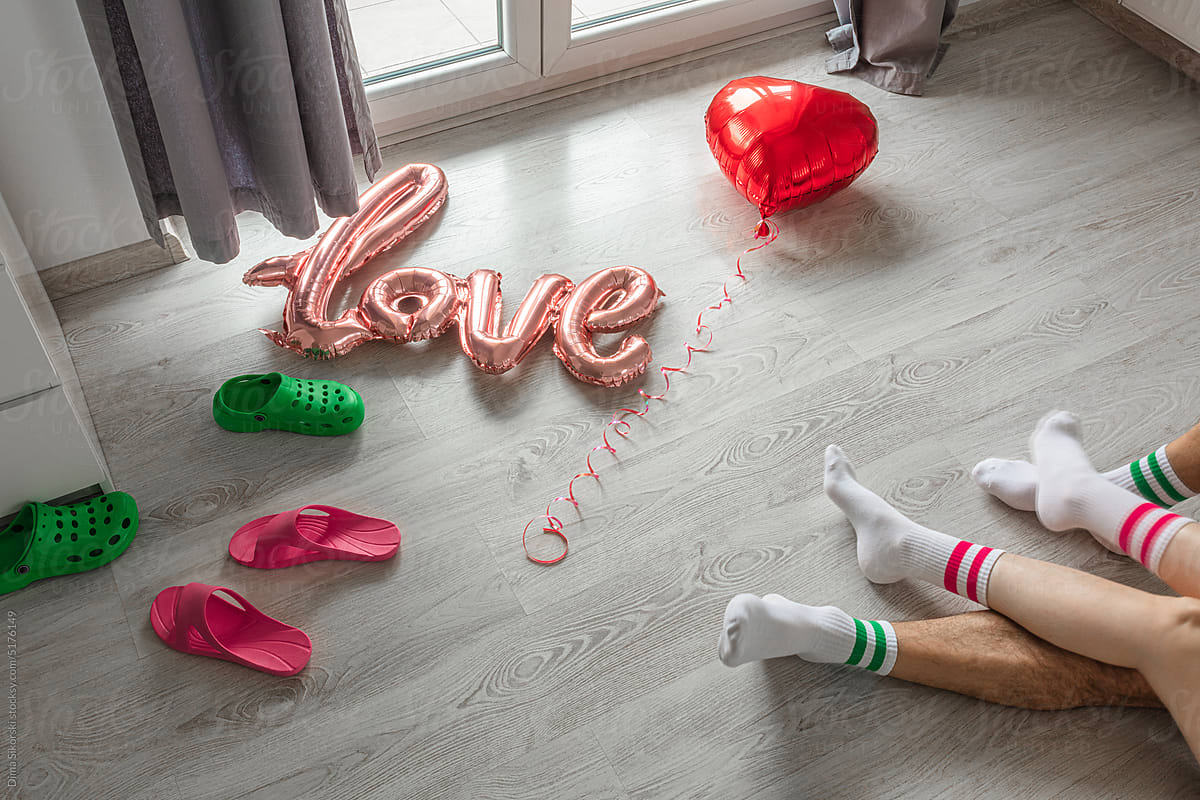 Two pairs of feet on the floor near the balloons on Valentine\'s Day