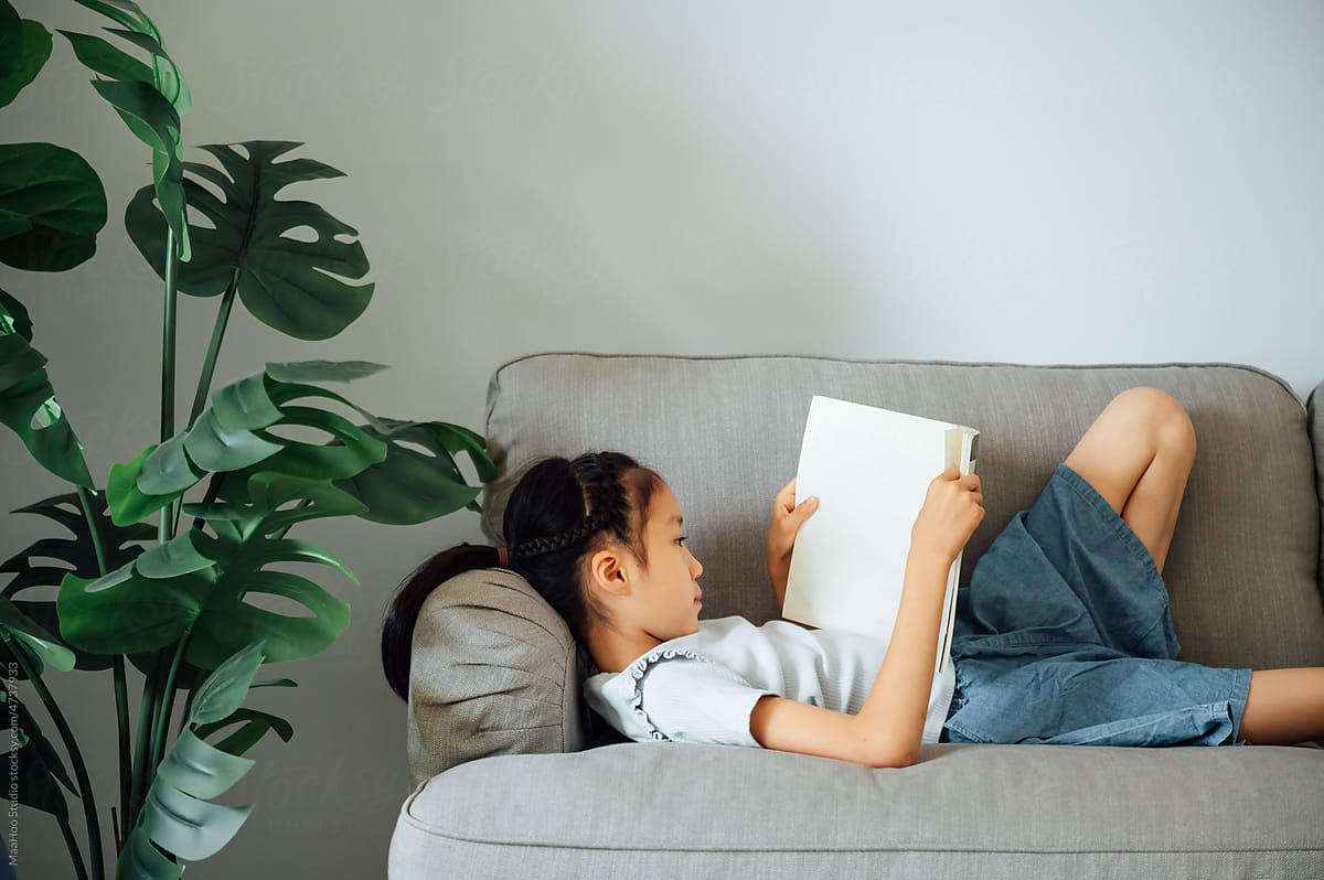 Cute girl reading books on couch