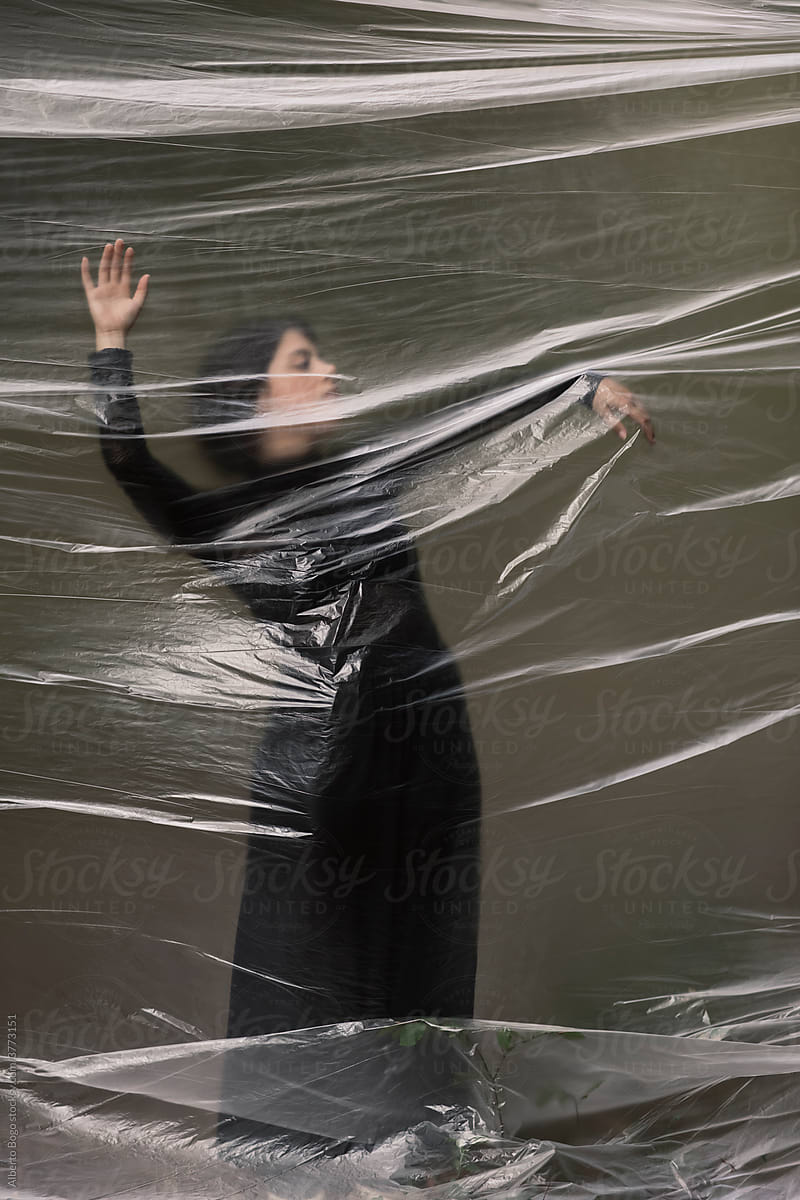 Young Woman Dancing In The Forest Through A Plastic Sheet