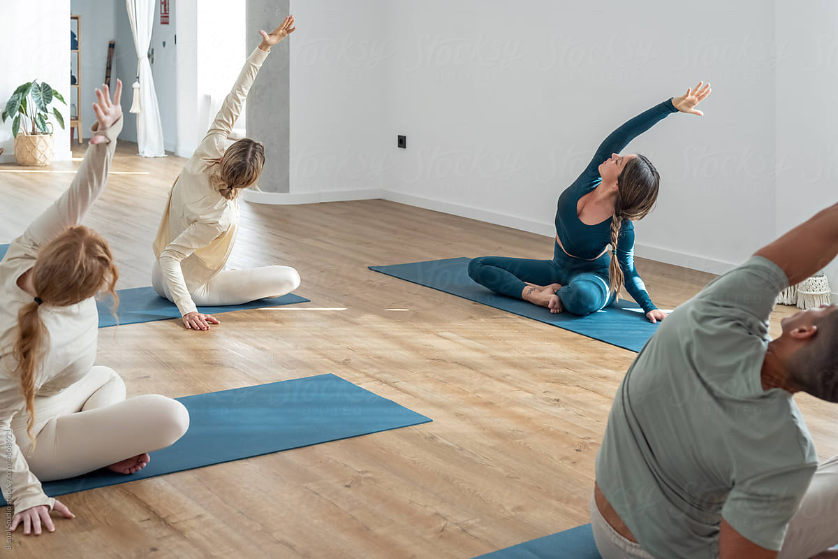 People stretching during yoga session with trainer