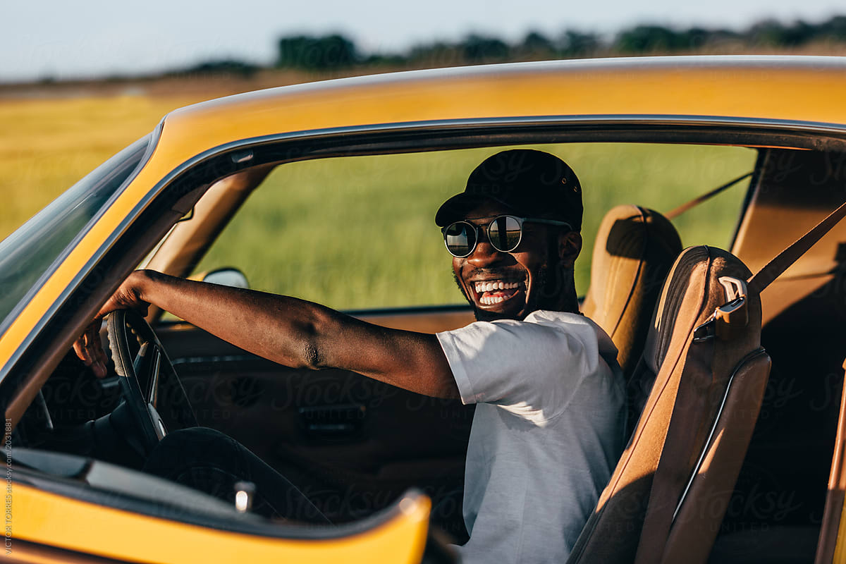 Black cheerful man inside a car