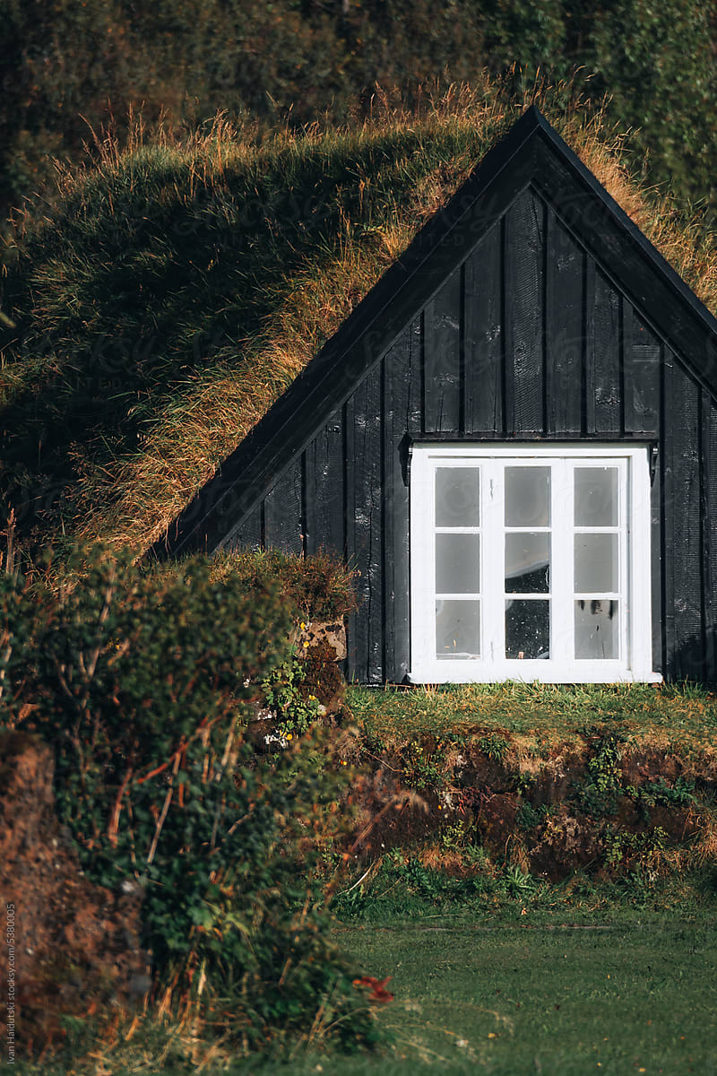Black wooden cabin with grass roof in Icelandic countryside.