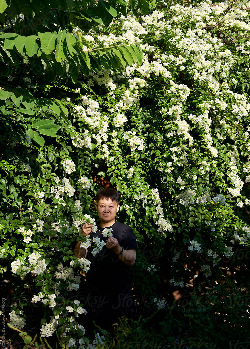 Asian woman inside blooming white bougainvillea