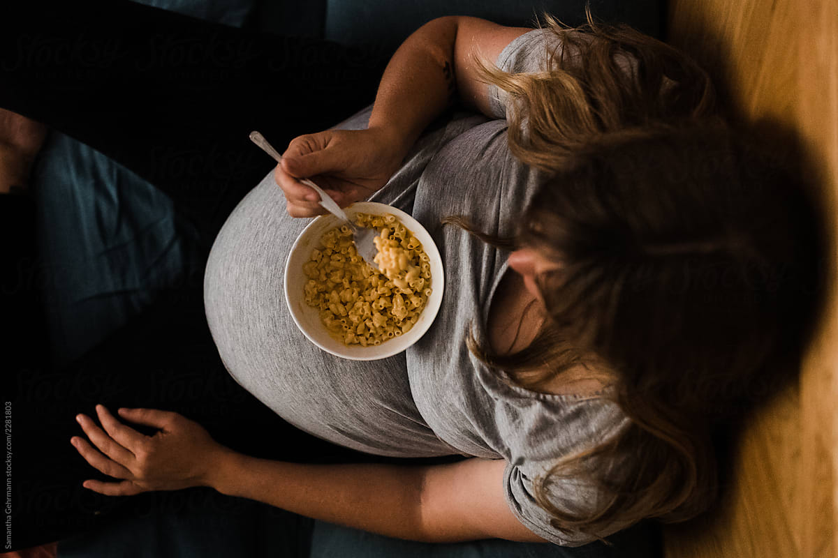 pregnant woman eating from bowl balanced on stomach