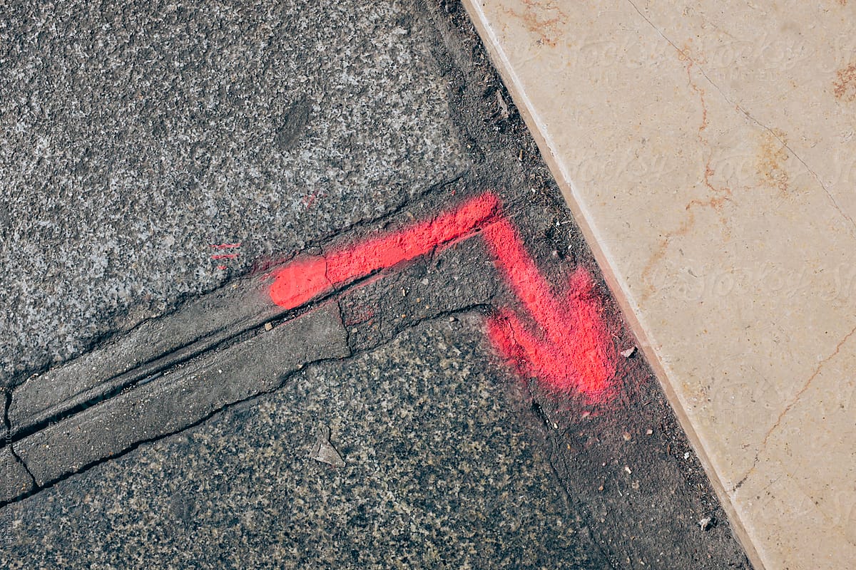 Red spray painted arrow on urban sidewalk