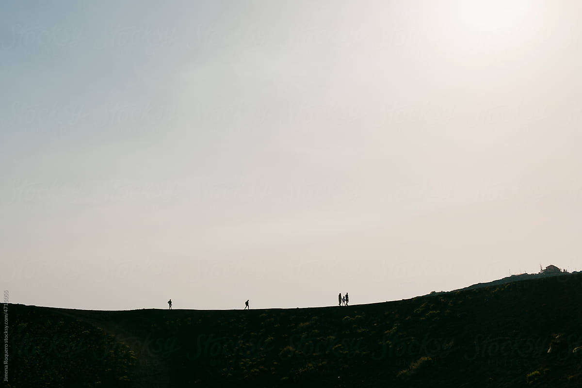 Silhouettes of people on top of mountain in backlight