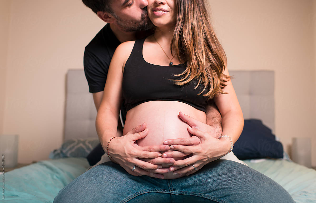 Pregnant couple embracing belly together