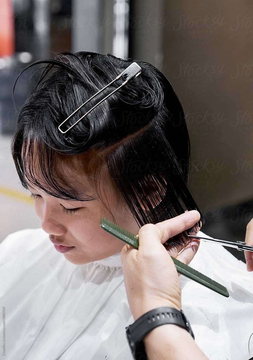 Asian Chinese little girl getting a haircut, in a hair salon