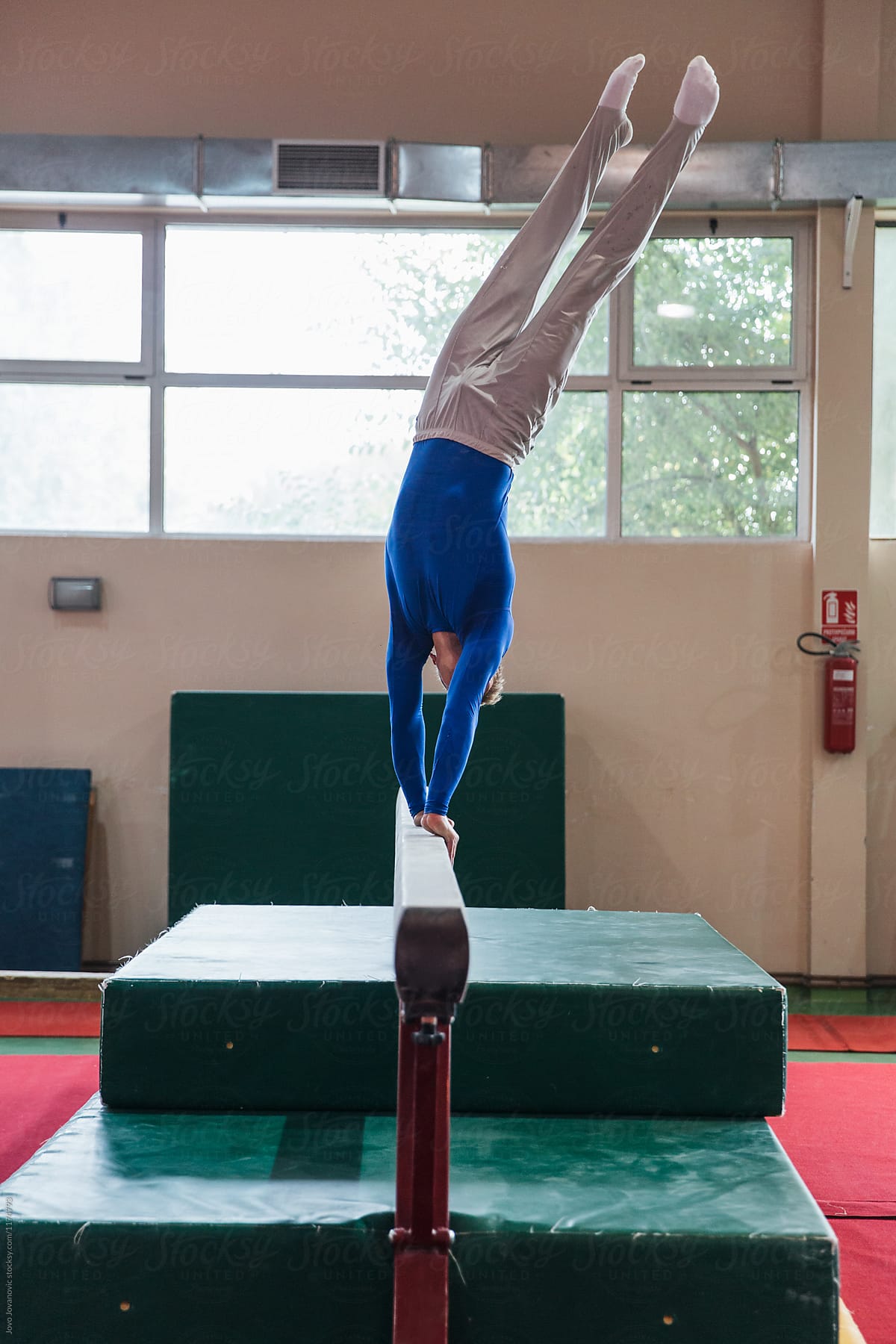 Young male gymnast dismounting off handstand