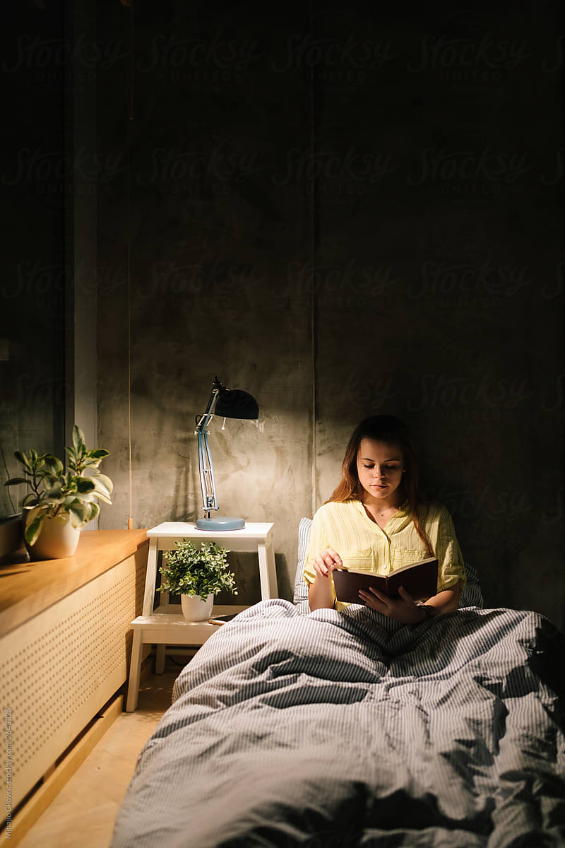 Young woman reading a book in bed