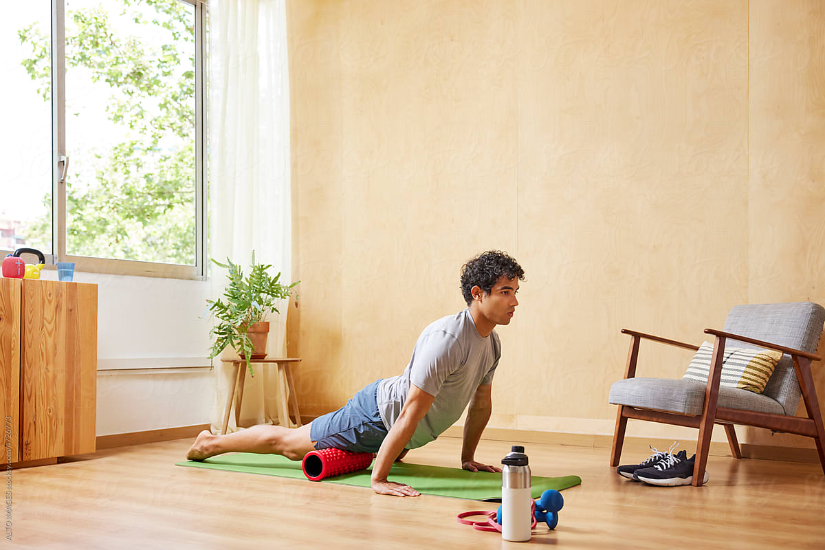 Young man doing Upward Facing Dog yoga asana at home
