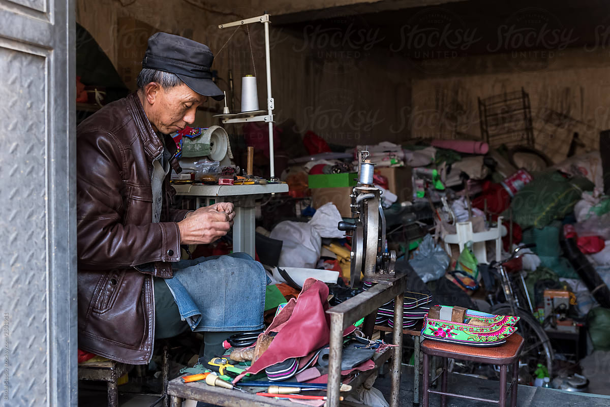A Cobbler sewing a shoe at his workshop