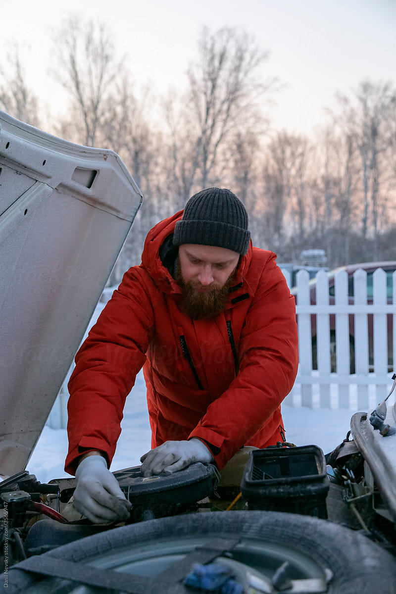 Man repairing car air filter in wintertime