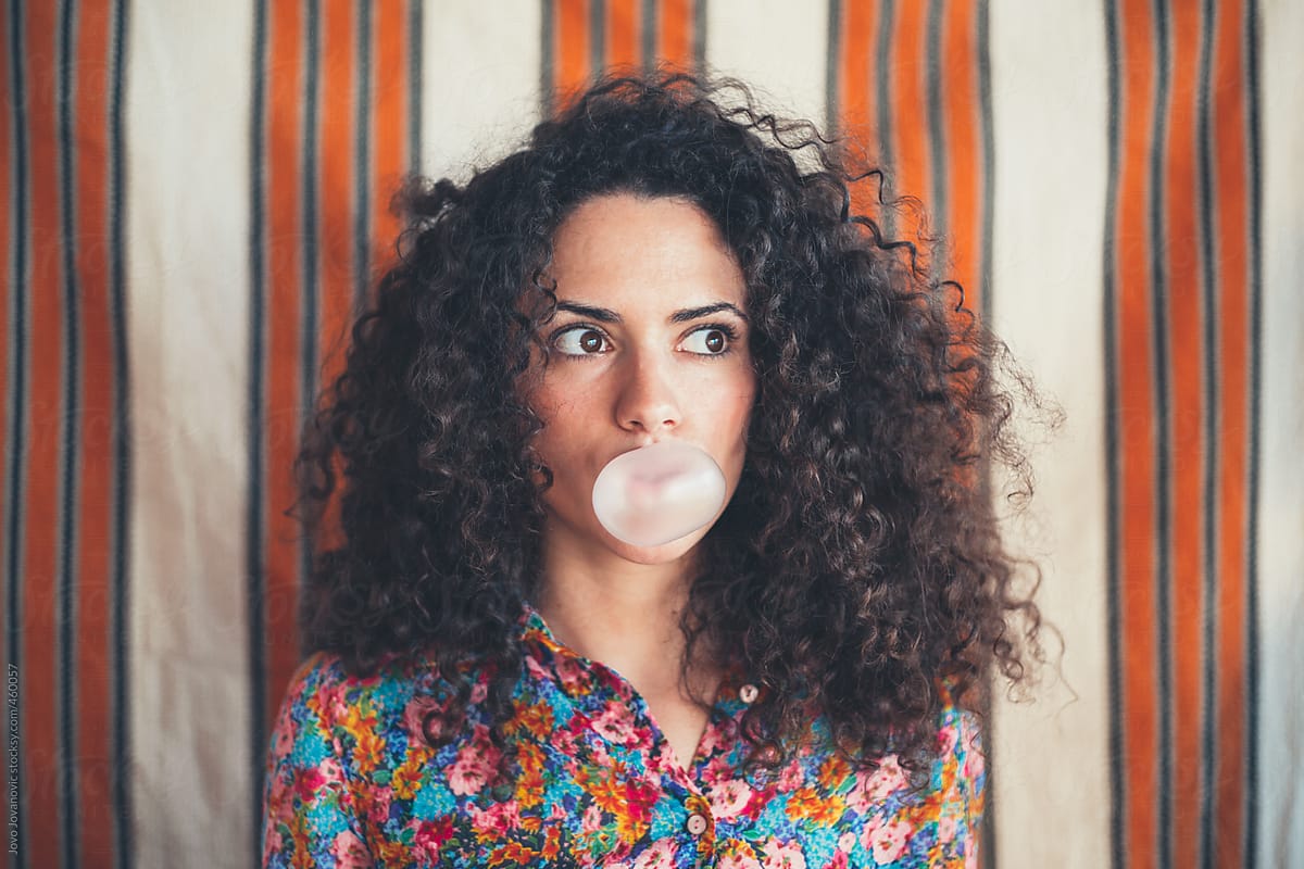 Girl With Curly Hair Blowing A Bubble With A Pink Bubble Gum By Jovo