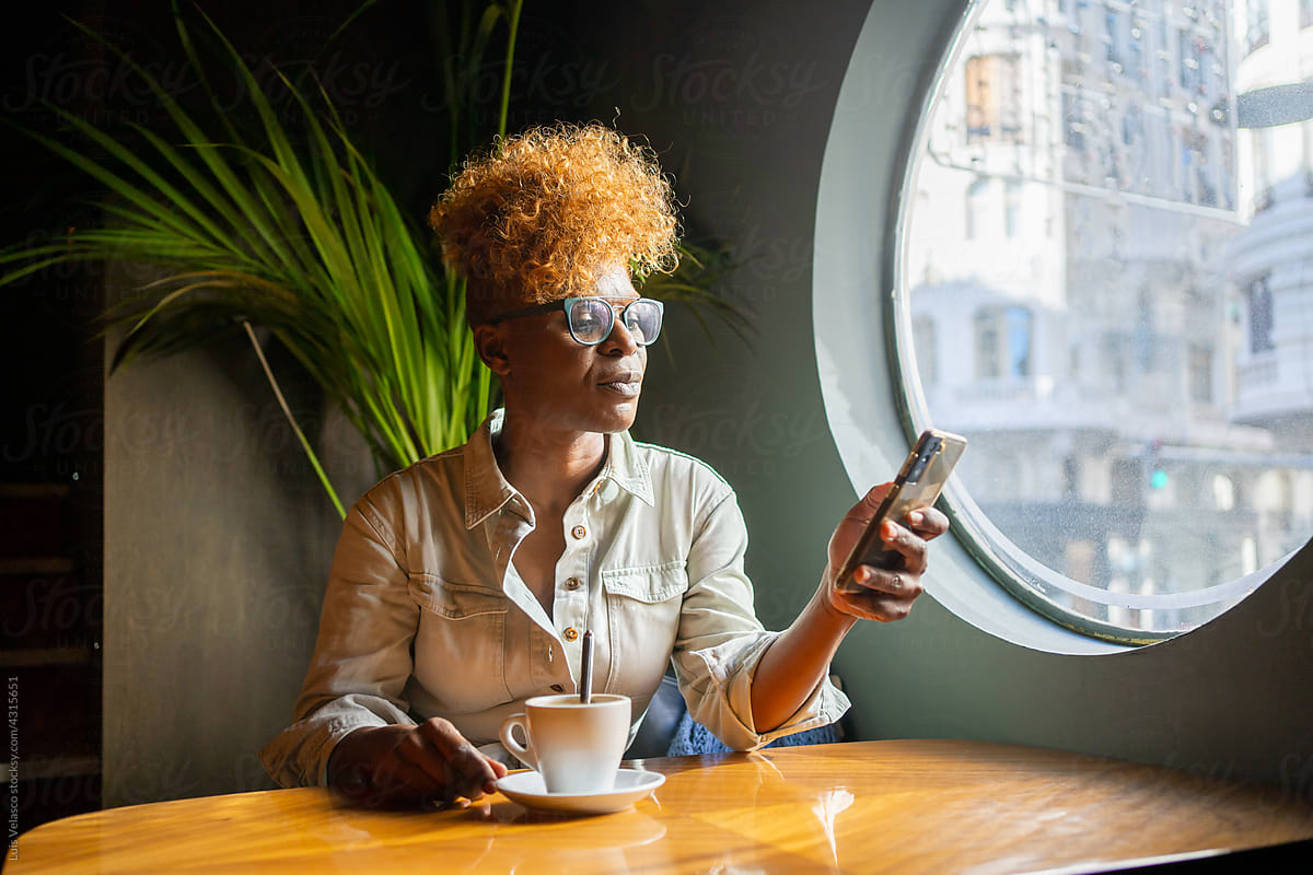 Modern Black Woman Checking The Phone In A Cafe.