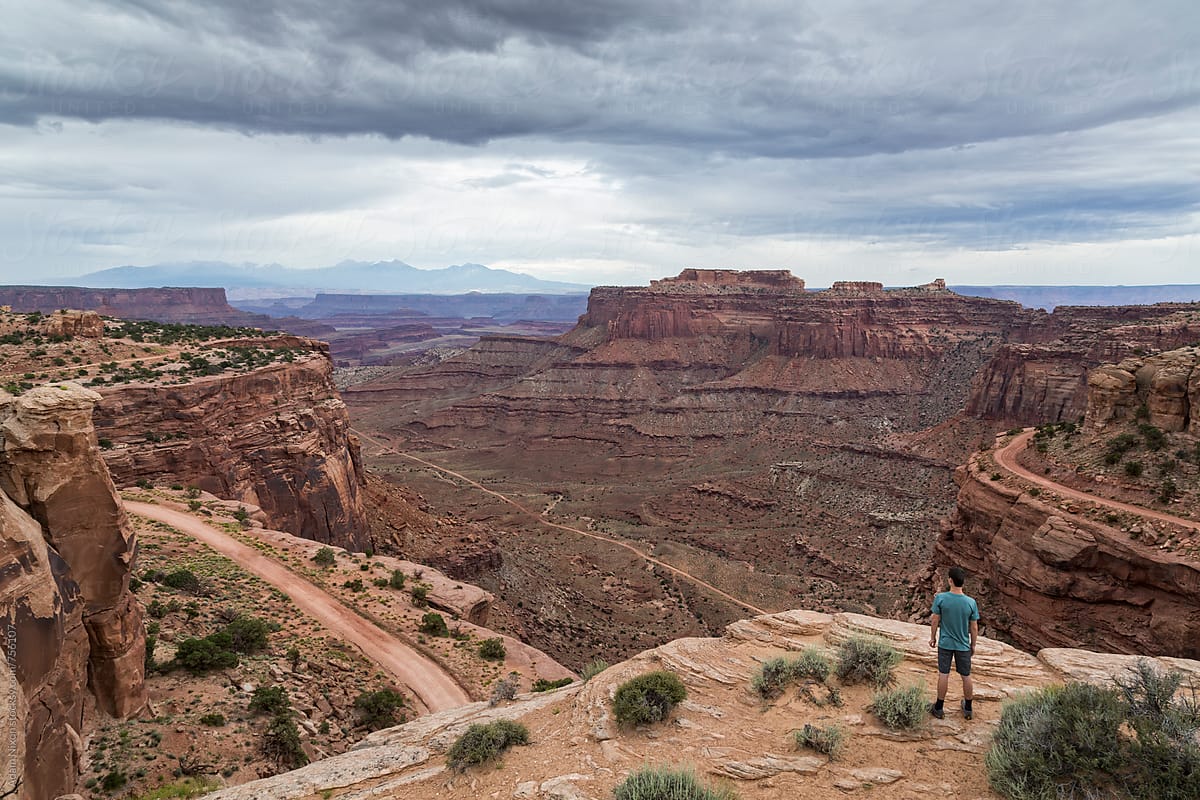 Teenage boy standing on the edge of a cliff, looking out over Canyonlands National Park Utah